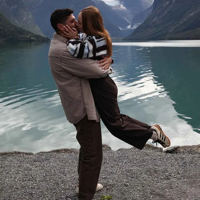 Par som feirer forlovelsen ved vannet.