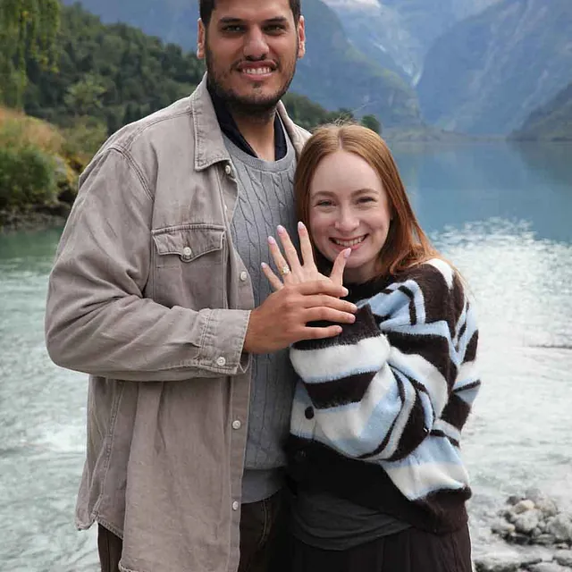 Smilende par på forlovelsesfotografering ved fjorden.