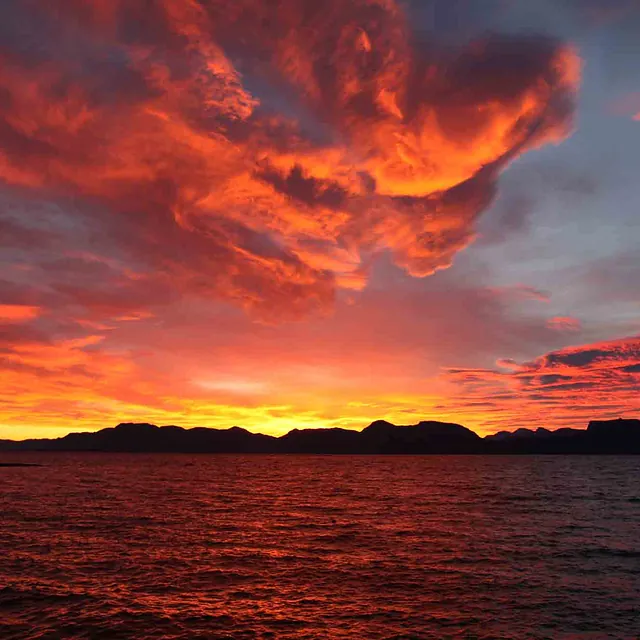 Dramatiske og rødglødende skyer under en intens solnedgang.