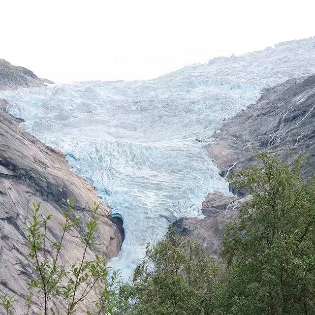 Landskapsbilde av en stor, blålig isbre mellom bratte fjellsider.