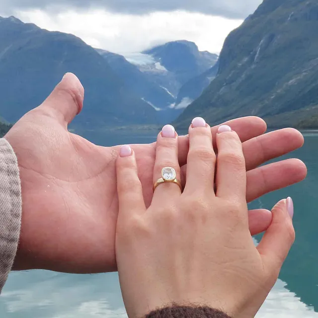 Par som viser frem forlovelsesring ved fjorden.