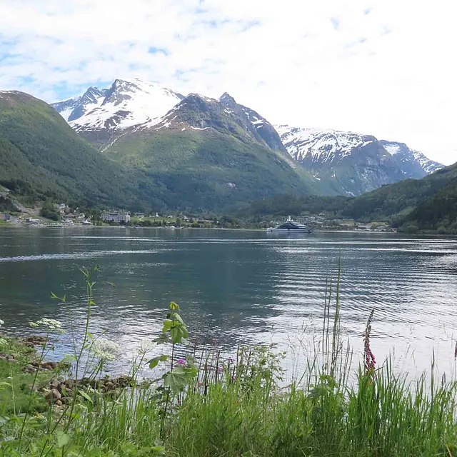 Naturfoto av blikkstille vann omkranset av frodige, grønne fjellsider.