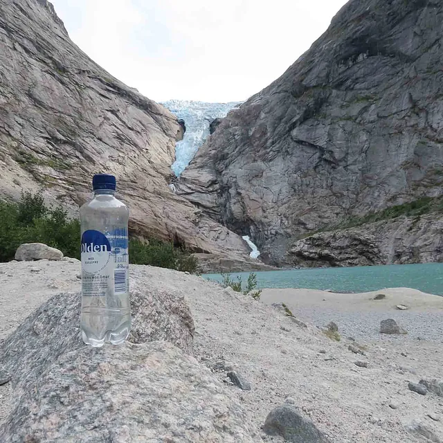 Naturfoto av en vannflaske på bakken foran Briksdalsbreen i Olden.