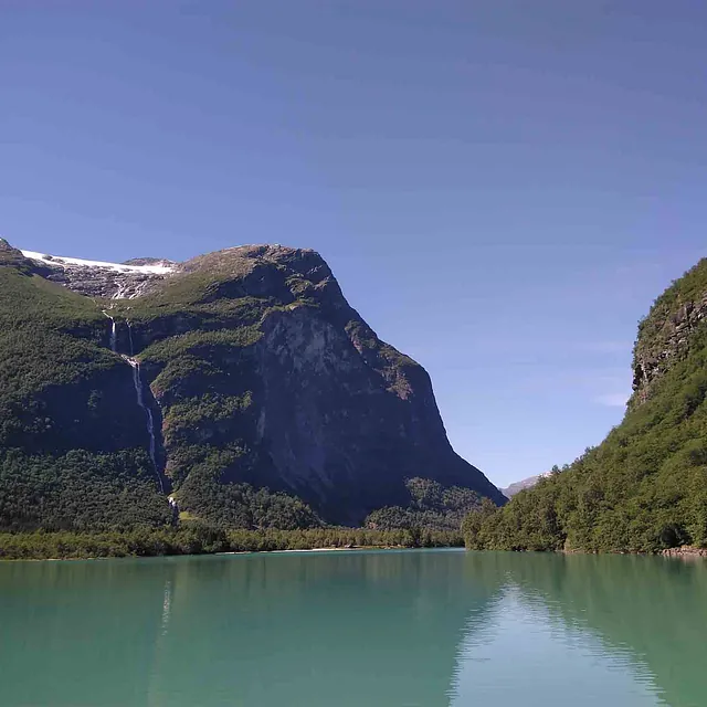 Turkisblått vann omkranset av bratte, majestetiske fjellsider.