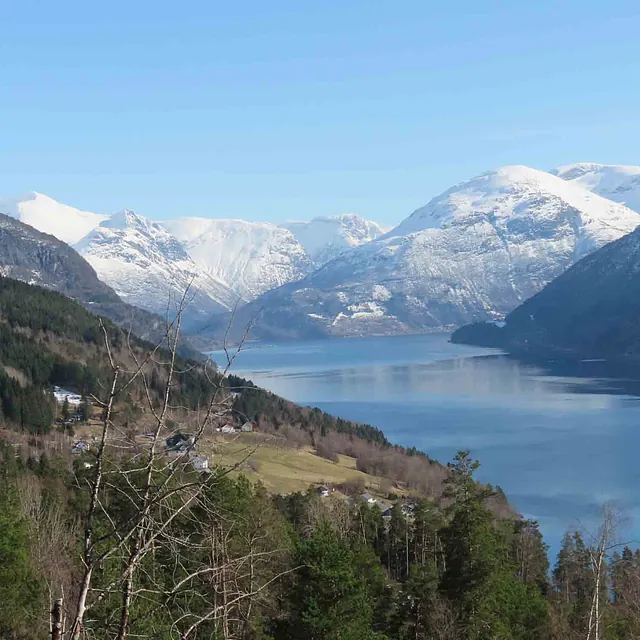 Panoramautsikt over fjorden omkranset av majestetiske, snødekte fjell i Olden.